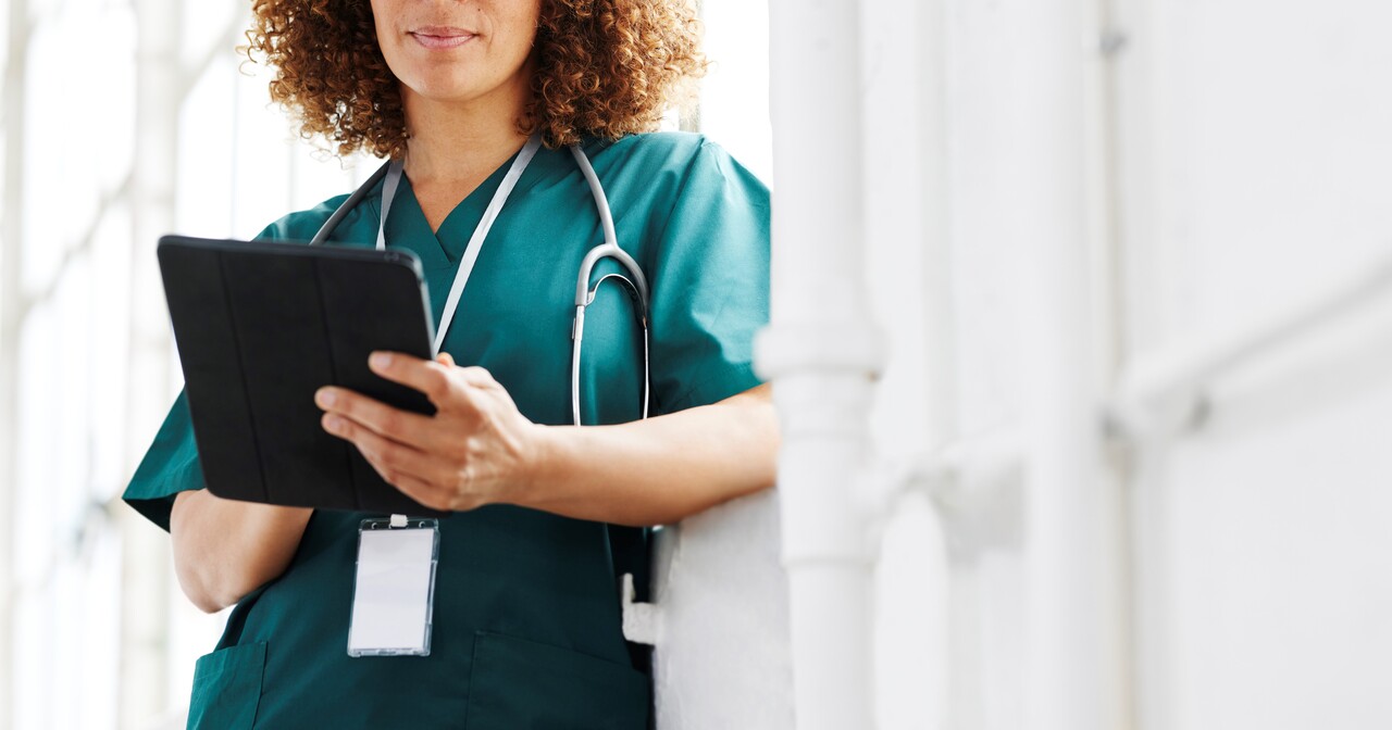 green_scrubs_and_curly_hair_looking_at_a_tablet